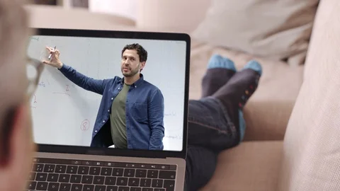 Student watching lesson online from sofa and studying from home, professor doing Stock Footage 127860795