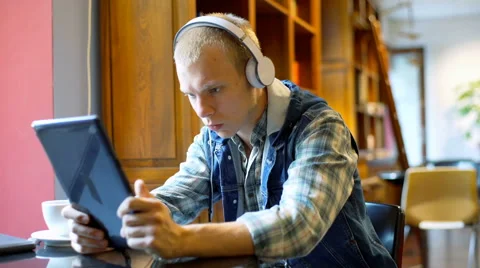 Student watching something on tablet and drinking coffee in the library Stock Footage 67542102