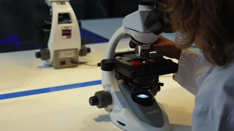 A Student in a White Coat Makes Observation With a Microscope Stock Footage 254515711