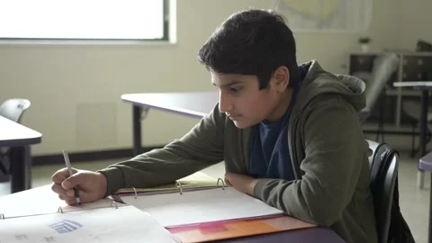 Student working at desk in classroom 스톡 동영상 221034308