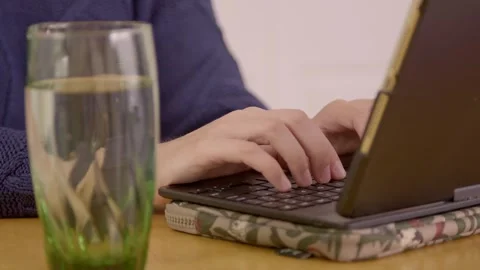 Student working on his computer with a glass of water next to him Stock Footage 307327265