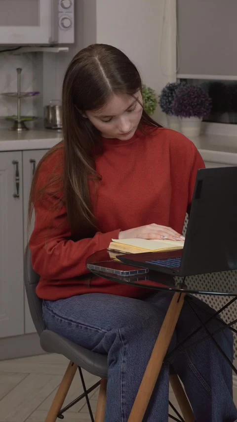 Student working from home using laptop and textbook Stock Footage 311780790