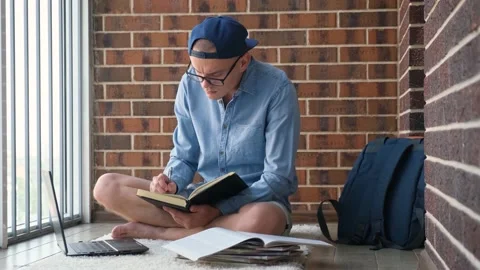 Student working on laptop with textbooks sitting on the floor Video stock 201613900