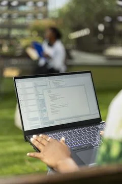 Student working on programming code on laptop during campus study session Stock Photos