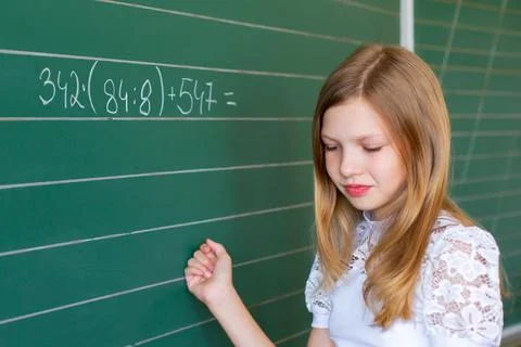 Student works on math problem at school board during class time with classm.. Stock Photos