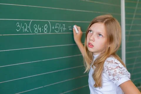Student works on math problems at a school board during a classroom session.. Stock Photos
