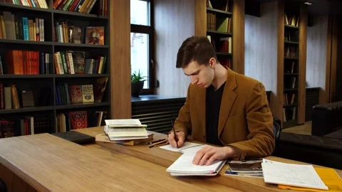 A student works at a table in the library and takes notes Stock Footage 155962972
