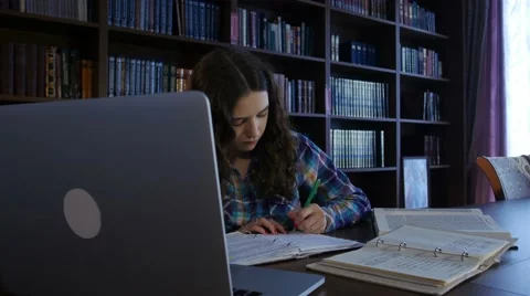 The student writes in a notebook in the library. 4K Stock Footage 63503160