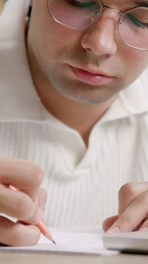 Student writes notes with pencil in pad studying at laptop Stock Footage 313927011