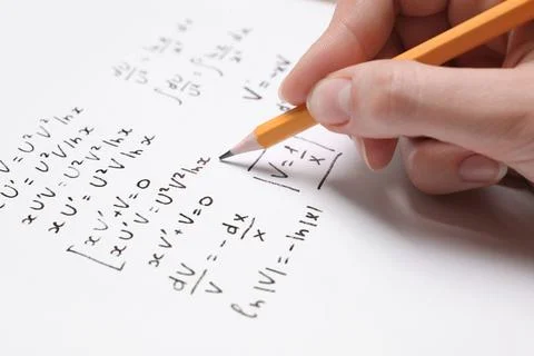 Student writing different mathematical formulas on paper, closeup Fotos de archivo