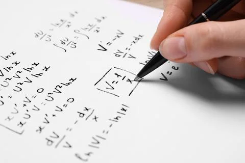 Student writing different mathematical formulas on paper, closeup Fotos de archivo