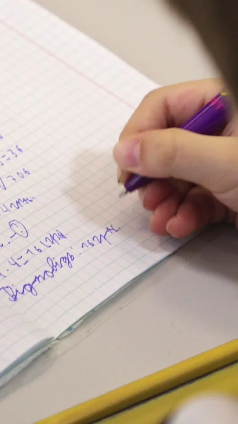 A student writing math equations in a grid notebook with a purple pen, high.. Stock Footage 339861283