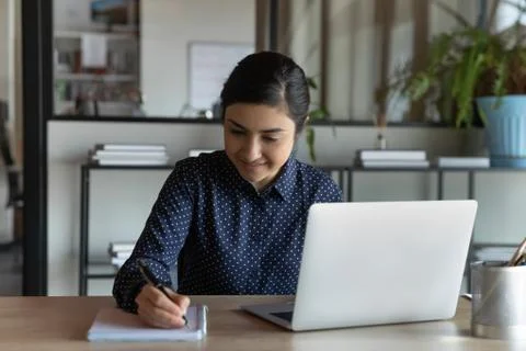Student writing on notepad do assignment seated at desk Foto stock