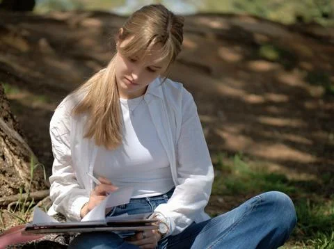 Student writing notes on the grass in a park Stock Photos