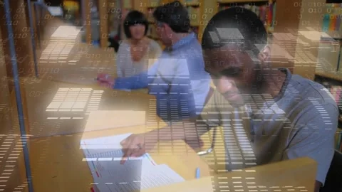 Student writing notes in library cubicle as pair pointing text initiating code Stock Footage 328978442