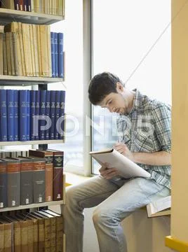 Student Writing Notes On Windowsill In Library Stock Photos