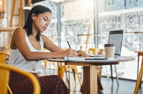 Student writing, taking notes or doing a project assignment in cafe or Stock Photos