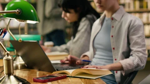 Student writing on textbook and loses focus after receiving phone notification Stock Footage 336360541