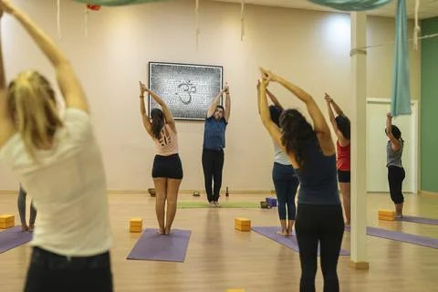 Students and instructor in yoga class practicing Nitambasana pose Stock Photos