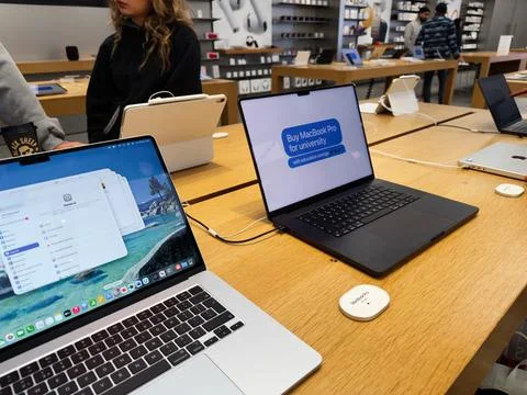 Students and shoppers explore a tech store with MacBook Pro laptops on displa Stock Photos