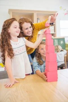Students and teacher stacking blocks in classroom Stock Photos