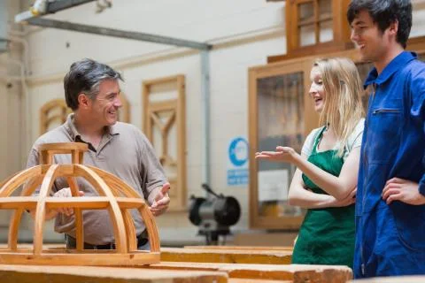 Students and teacher talking and laughing in woodwork class Stock Photos