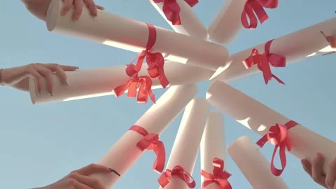 Students are celebrating their graduation by holding their diplomas up in the Stock Footage 317416600