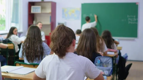 Students are sitting at their desks in the classroom, while a classmate is .. Stock Footage 345668682