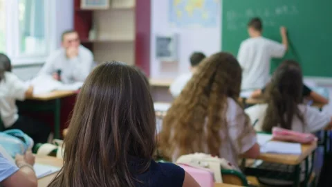 Students are sitting at their desks in the classroom, while a classmate is .. Stock Footage 345668756