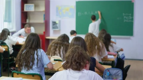 Students are sitting at their desks in the classroom, while a classmate is .. Stock Footage 345669097