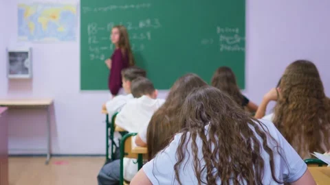 Students are sitting at their desks in the classroom, while a classmate is .. Stock Footage 345669166