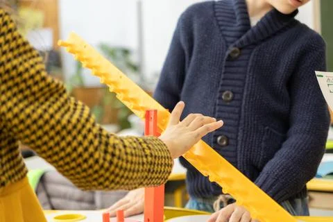 Students assemble a yellow plastic structural kit in a classroom to learn p.. Stock Photos