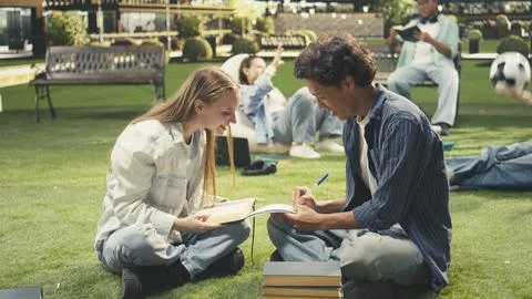 Students celebrating teamwork with high five on outdoor campus lawn Stock Photos