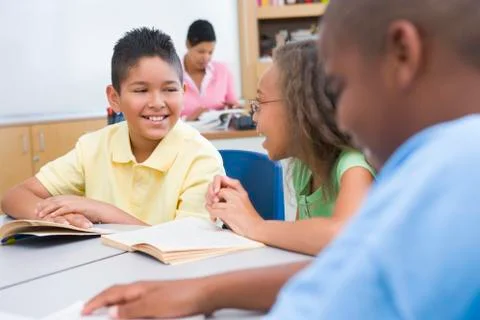 Students in class reading with teacher in background (selective focus) Stock Photos