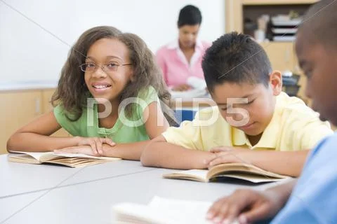 Students in class reading with teacher in background (selective focus) Stock Photos