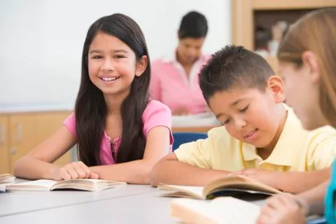 Students in class reading with teacher in background (selective focus) Stock Photos