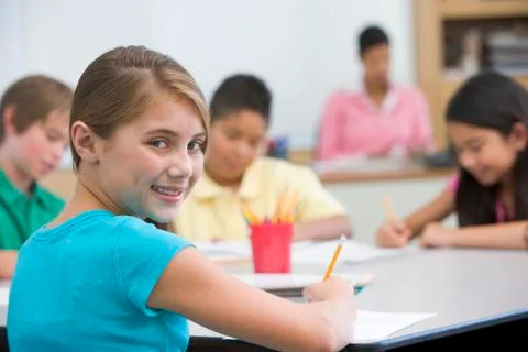 Students in class taking notes with teacher in background (selective focus) Stock Photos