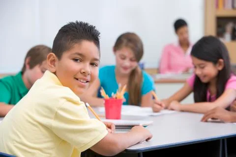 Students in class taking notes with teacher in background (selective focus) Stock Photos