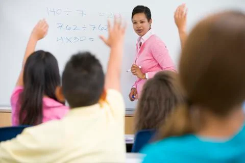 Students in class volunteering for teacher at front board (selective focus) Stock Photos