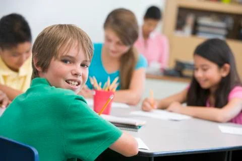 Students in class writing with teacher in background (selective focus) Stock Photos