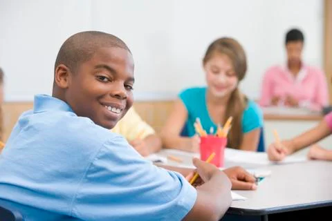 Students in class writing with teacher in background (selective focus) Stock Photos
