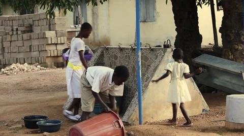 STUDENTS CLEANING UP AROUND FAUCETS WHILE A LARGE BUCKET IS FILLED WITH WATER Stock Footage 60521760