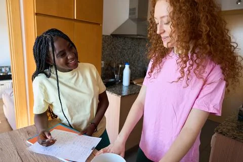 Students collaborating on homework in kitchen setting Stock Photos