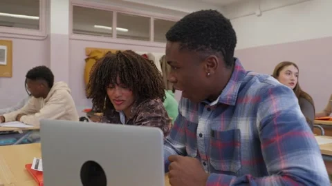 Students collaborating on laptop in classroom setting Stock Footage 301677833