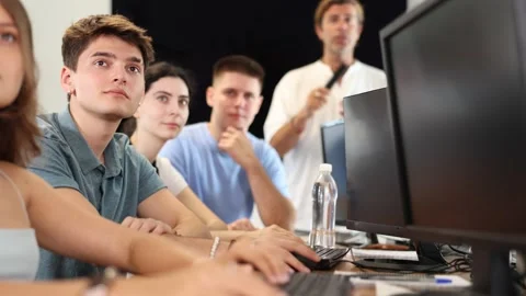 Students of computer courses sit in class near PC, watch to teacher and listen Stock Footage 306454024