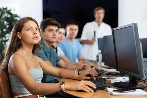 Students of computer courses sit in class near PC, watch to teacher and listen Foto stock