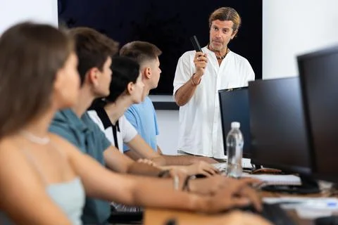 Students of computer courses sit in class near PC, watch to teacher and listen 스톡 사진