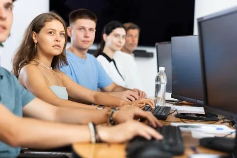 Students of computer courses sit in class near PC, watch to teacher and listen Stock Photos