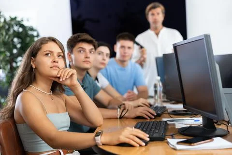 Students of computer courses sit in class near PC, watch to teacher and listen Stock Photos