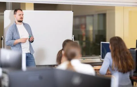 Students of computer courses sit in class, watch to teacher and listen to Stock Photos
